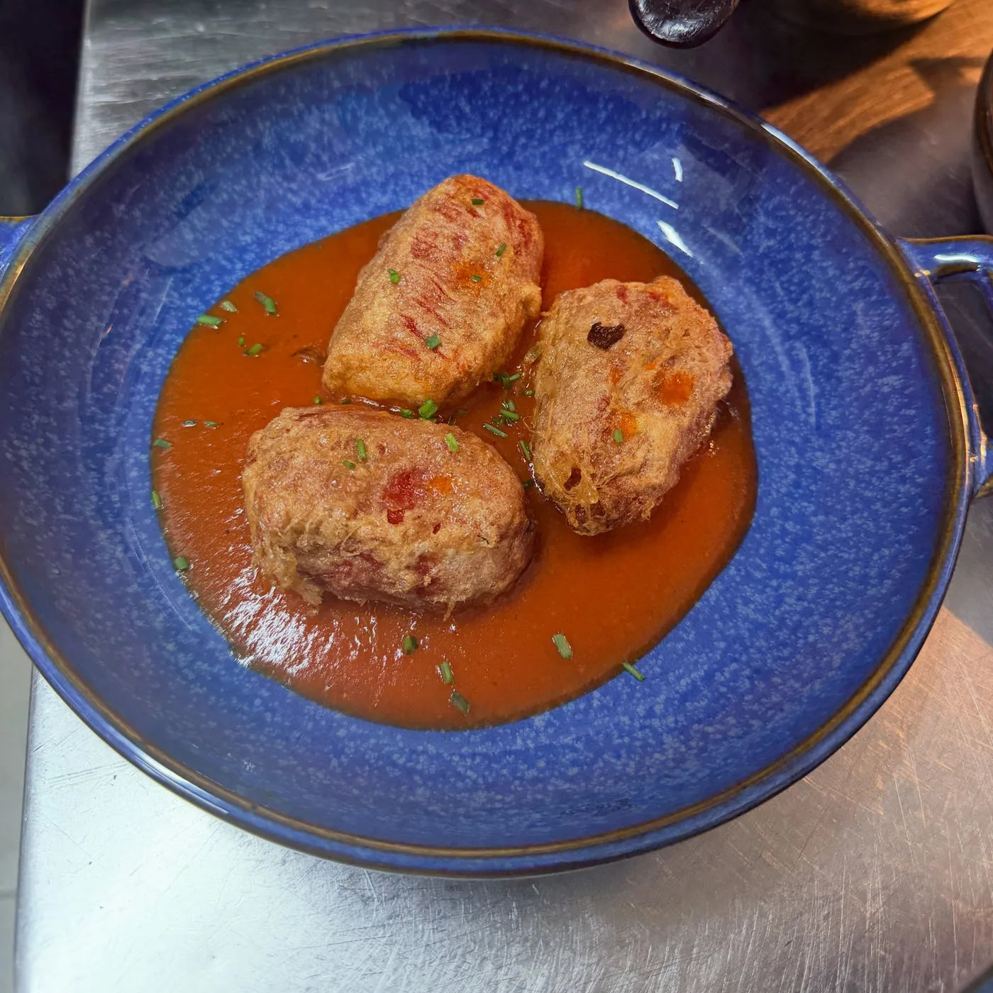 Guiso casero de Ohana en cazuela azul, sobre salsa de tomate