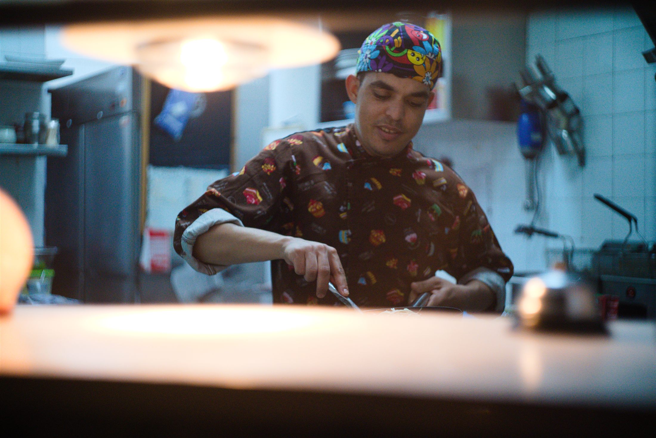 El cocinero de Ohana emplatando en la cocina, con bandana de colores
