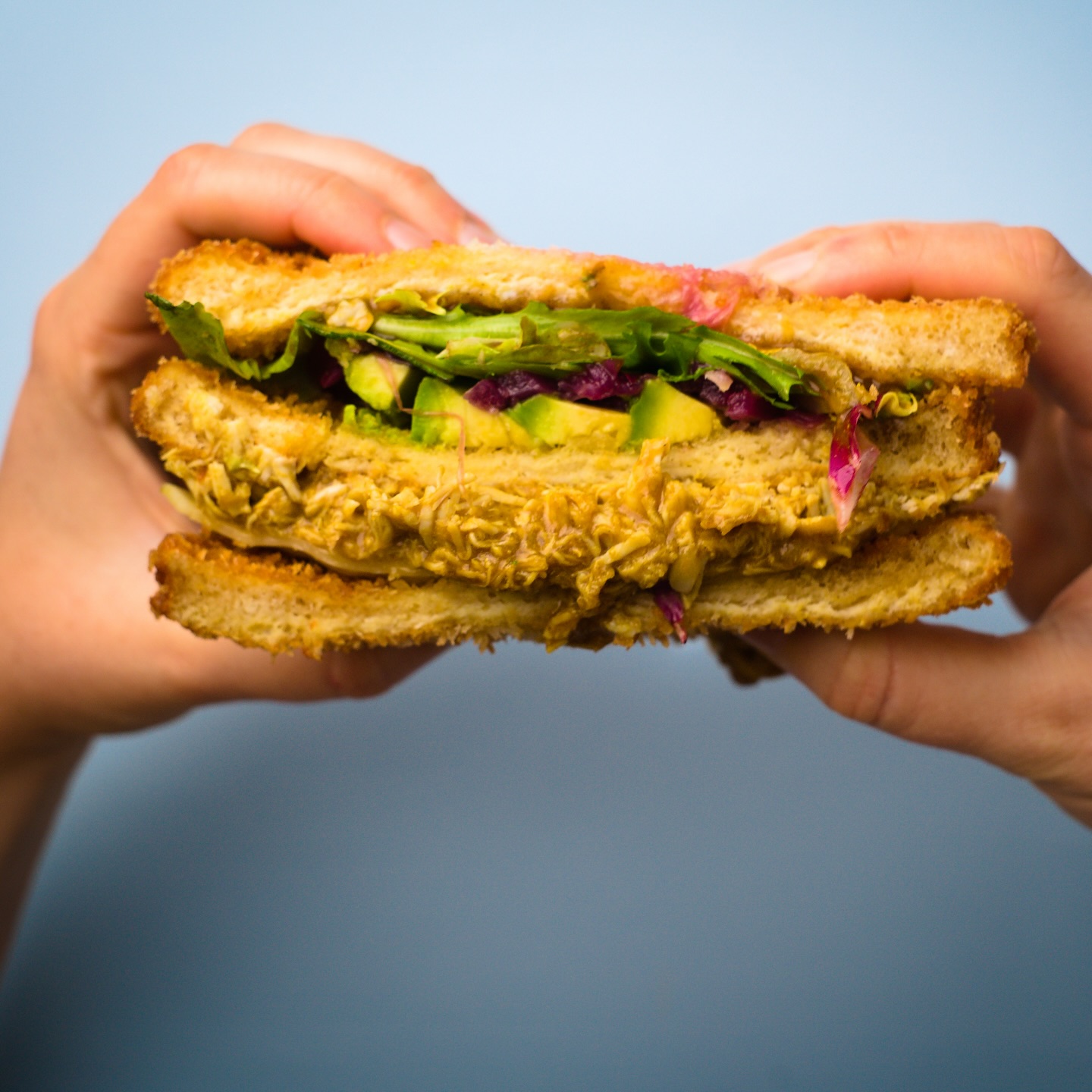 El sándwich de pollo panko en mano